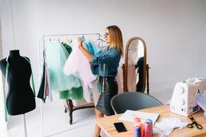 atractivo hembra Moda diseñador es trabajando en su taller. elegante mujer en proceso de creando nuevo ropa recopilación. foto