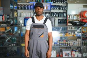 retrato de un hermoso africano vendedor en un auto partes almacenar. el concepto de coche reparar foto