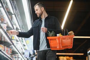 retrato de sonriente hombre caminando con su carretilla en pasillo a supermercado. foto