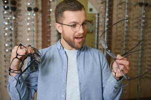 Healthcare, Eyesight And Vision Concept. Happy man choosing glasses at optics store, selective focus photo