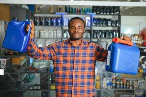 seller man with canister of motor oil in auto store photo