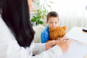 Young female psychologist working with little child in office photo