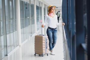 Girl traveler walking with carrying hold suitcase in the airport. Tourist Concept. Woman walks through airport terminal with luggage. travel concept photo