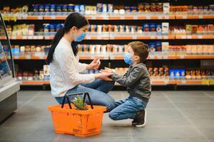 woman disinfects her son hands in the store during coronavirus and flu outbreak. photo