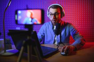 A video blogger records content in his studio. The host of the video blog is a young man who is very enthusiastic about telling his subscribers a story. photo