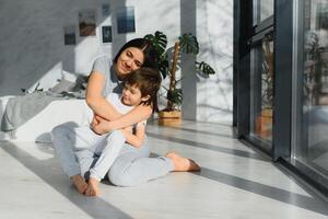 Mom is hugging her son sitting on the floor in the room. Family home shoot. photo