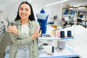 Young woman working as seamstress in clothing factory. photo