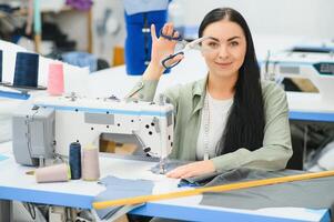 Portrait of a beautiful seamstress carrying a tape measure and working in a textile factory photo