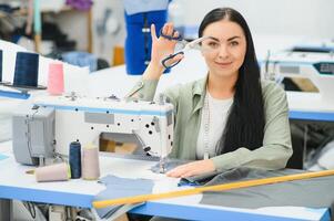 Portrait of a beautiful seamstress carrying a tape measure and working in a textile factory photo