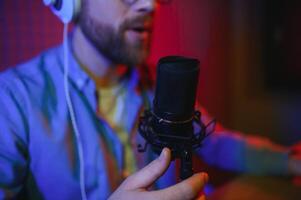 Young man recording or streaming podcast using microphone at his small broadcast studio. Content creator. photo