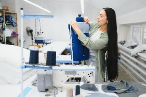 Portrait of a beautiful seamstress carrying a tape measure and working in a textile factory photo