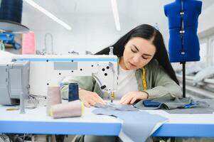 Portrait of a beautiful seamstress carrying a tape measure and working in a textile factory photo