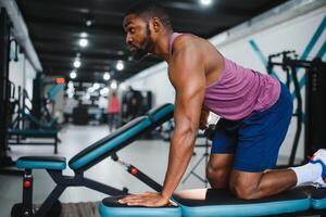 Weight training African doing bodybuilding in gym. photo