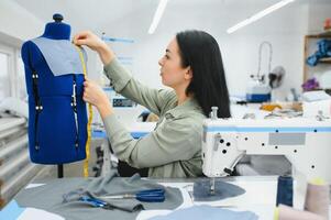 Portrait of a beautiful seamstress carrying a tape measure and working in a textile factory photo