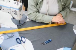 Portrait of a beautiful seamstress carrying a tape measure and working in a textile factory photo