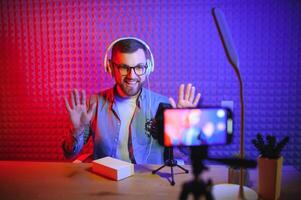 Young man recording or streaming podcast using microphone at his small broadcast studio. Content creator. photo