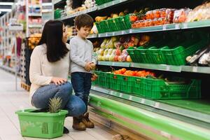 woman and child boy during family shopping with trolley at supermarket photo