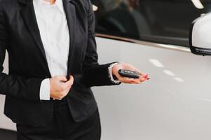 auto negocio, coche venta, consumismo y personas concepto - contento mujer tomando coche llave desde comerciante en auto espectáculo o salón. foto