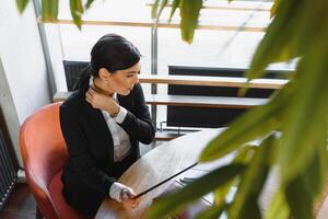 retrato de un elegante mujer de negocios utilizando tableta ordenador personal en un brillante moderno oficina foto