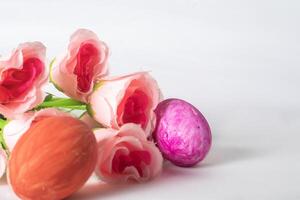Pascua de Resurrección huevos y rosado Rosa flores en un blanco antecedentes con espacio para texto. foto