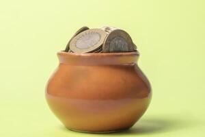 Coins in a clay pot on a green background. Money saving concept. photo