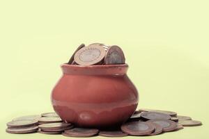 Coins in a red pot on a green background with copy space. photo