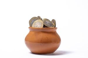 Coins in a clay pot on a white background. Saving concept. photo