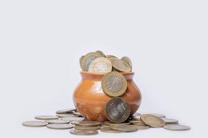 Coins in a clay pot on a white background with copy space. photo