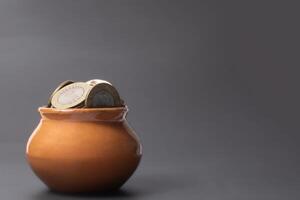 Coins in a clay pot on a gray background with copy space. photo