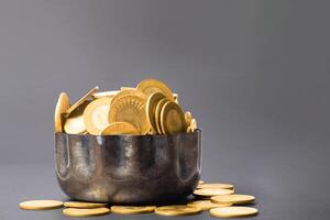 Golden coins in a copper bowl on a dark background photo