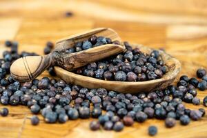 dried juniper berries on olive wood photo