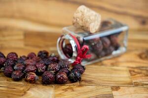 dietary supplement, dried rose hips on olive wood photo