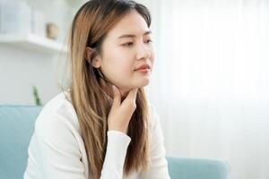 Asian woman put her hand on her neck due to a sore throat. female tonsillitis causes a inflammation. treated by taking water, taking antibiotics, consult a doctor, virus, corona virus, Influenza, flu photo