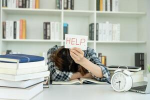 Asian student man have anxiety because of exams, male prepare for test and learning lessons in the library. stress, despair, haste, misunderstanding reading, discouraged, expectation, knowledge, tired photo