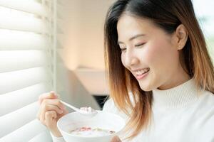 sano alimento. hermosa hembra niña disfrutar comer yogur, Granola, Fresco frutas en desayuno salud en casa. contento joven mujer sonrisa en Mañana bueno emoción. haciendo dieta, desintoxicación, dieta, limpiar comer, vegeta foto