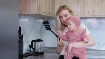 madre prepara comida participación bebé en su brazos. todos los días madres de la madre deberes video