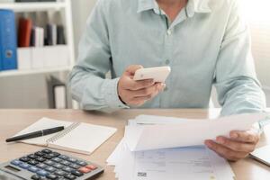 man use phone to scan barcode or QR codes to pay credit card bill after receiving document invoice online. payment, receive, paying electricity, digital payments without money, technology photo