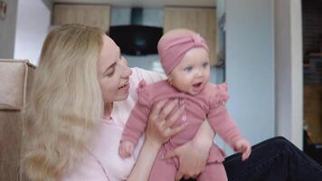 mãe e bebê menina com azul olhos e loiro cabelo sentado dentro frente do a Câmera video