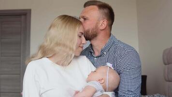 madre y padre sentar abrazando en el habitación mientras el niño duerme en su de la madre brazos. paternidad y maternidad. tradicional familia video