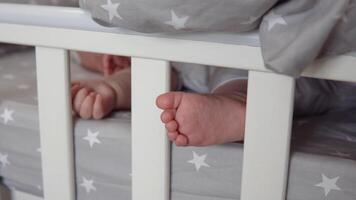 The sleeping baby's arm and leg are visible from under the blanket in the crib video