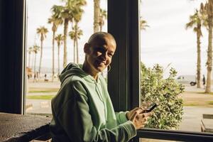 Woman with a bald hair style smiling using a device indoor photo