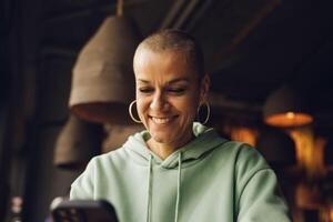 mujer con un calvo pelo estilo sonriente utilizando un dispositivo interior foto