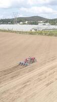 vertical vídeo de rojo tractor trabajando en el campo aéreo ver video