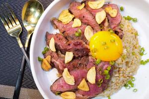 fried rice and grilled beef on top with yolk - Thai food photo