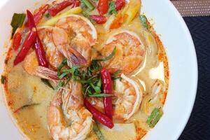 Tom Yam kung Spicy Thai soup with shrimp, seafood, coconut milk and chili in a bowl, close up photo