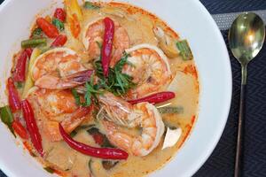 Tom Yam kung Spicy Thai soup with shrimp, seafood, coconut milk and chili in a bowl, close up photo