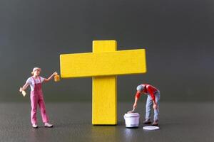 Good Friday concept, Miniature people, A yellow cross painted by an artist photo