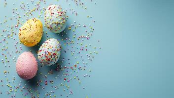 AI generated Easter eggs on blue background with sprinkles. Pink, yellow and blue pastel colors. Easter concept. Copy space. photo