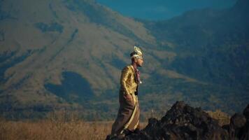 Man in traditional attire standing against mountain backdrop. video
