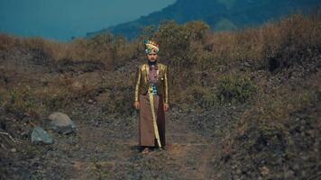 Man in traditional attire standing in a rugged landscape with mountains video